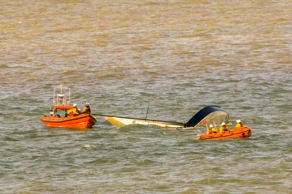 Calshot lifeboats with capsized racing yacht in Ower Bay