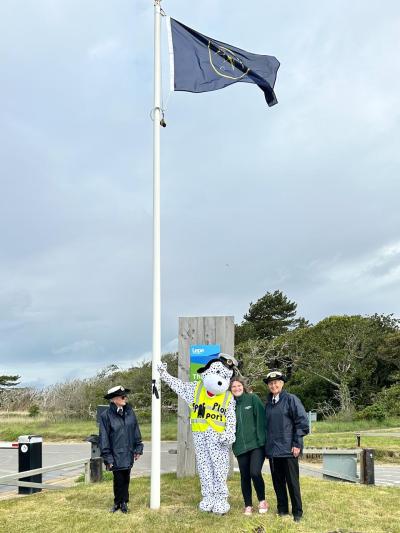 On NCI Awareness Day Station Mascot "Spot" hoists the NCI Flag 