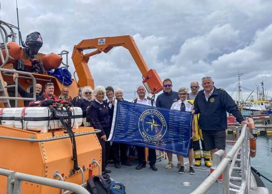 National Coastwatch 30th Anniversary Flag leaves NCI Gwennap Head, Porthgwarra Cove, for Penzance, carried by the RNLI Penlee AWLB Ivan Ellen