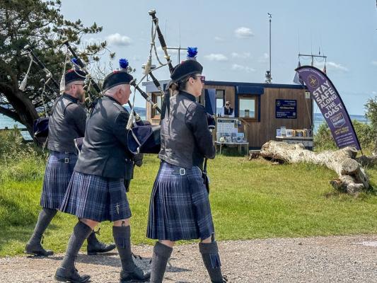 A Pipe Band marches past NCI Stone Point on D-Day Memorial Day